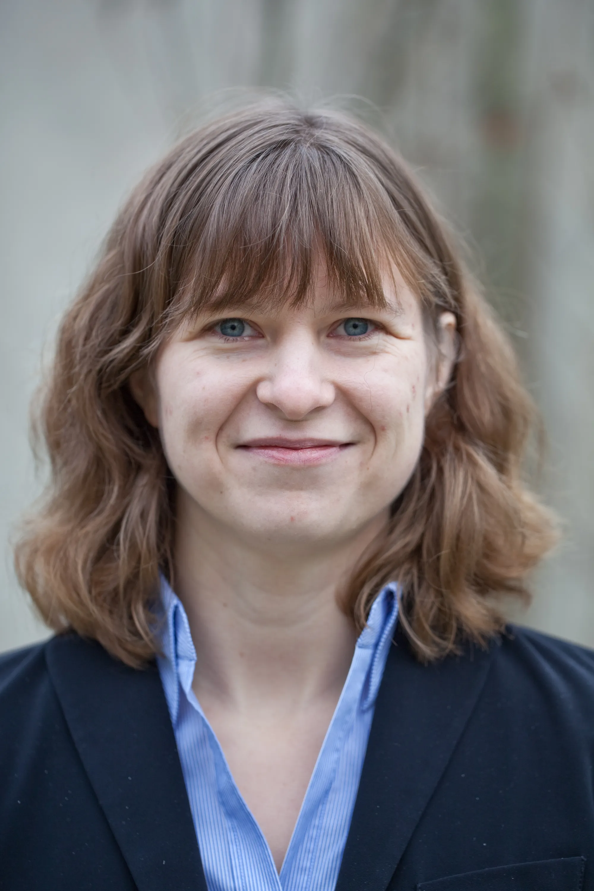 Porträt einer Frau mit schulterlangen Haaren, blauer Blazer, Naturhintergrund – Mitarbeiterfoto