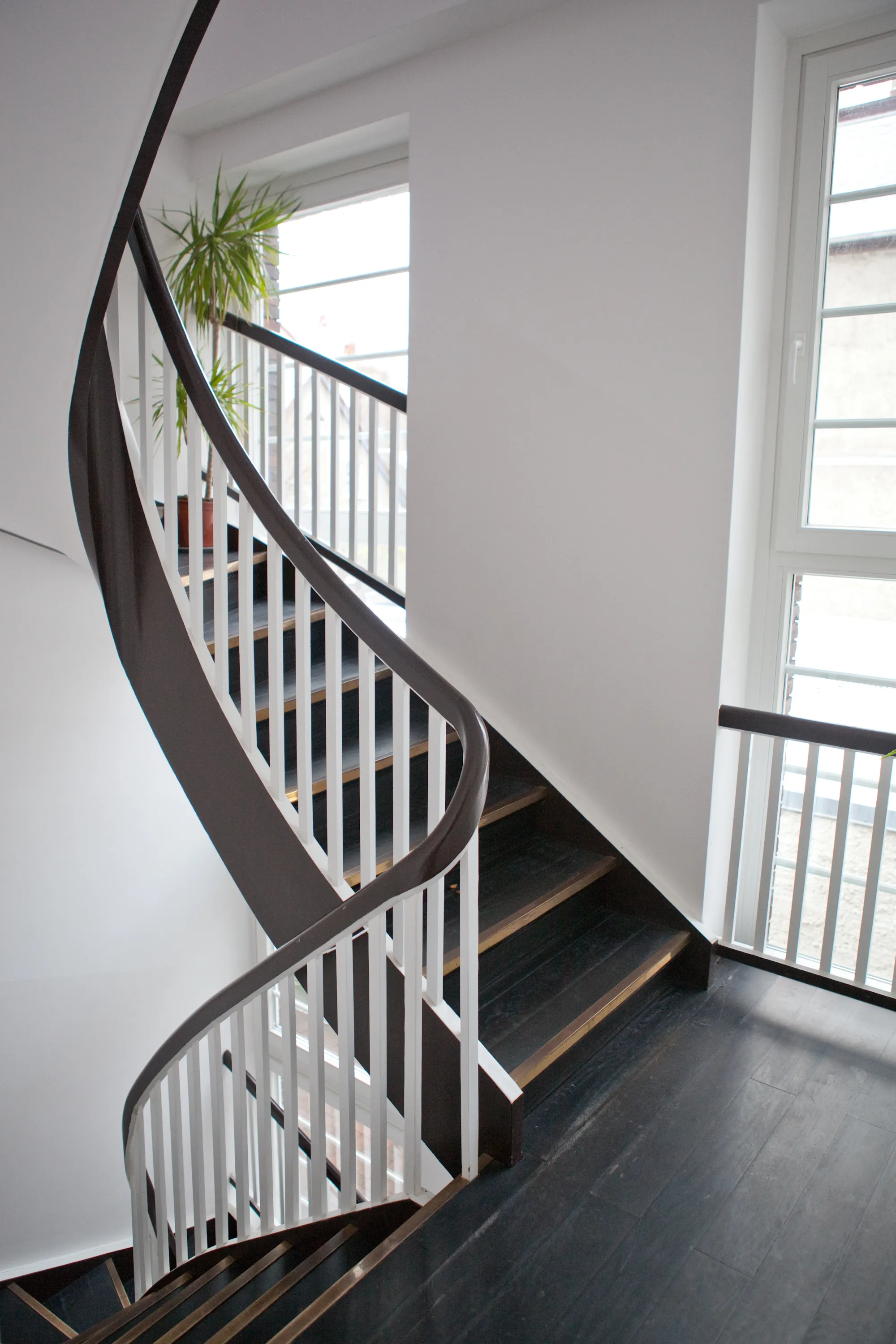 Modernes Treppenhaus mit schwarzen Handläufen und Oberlicht – Innenarchitektur.