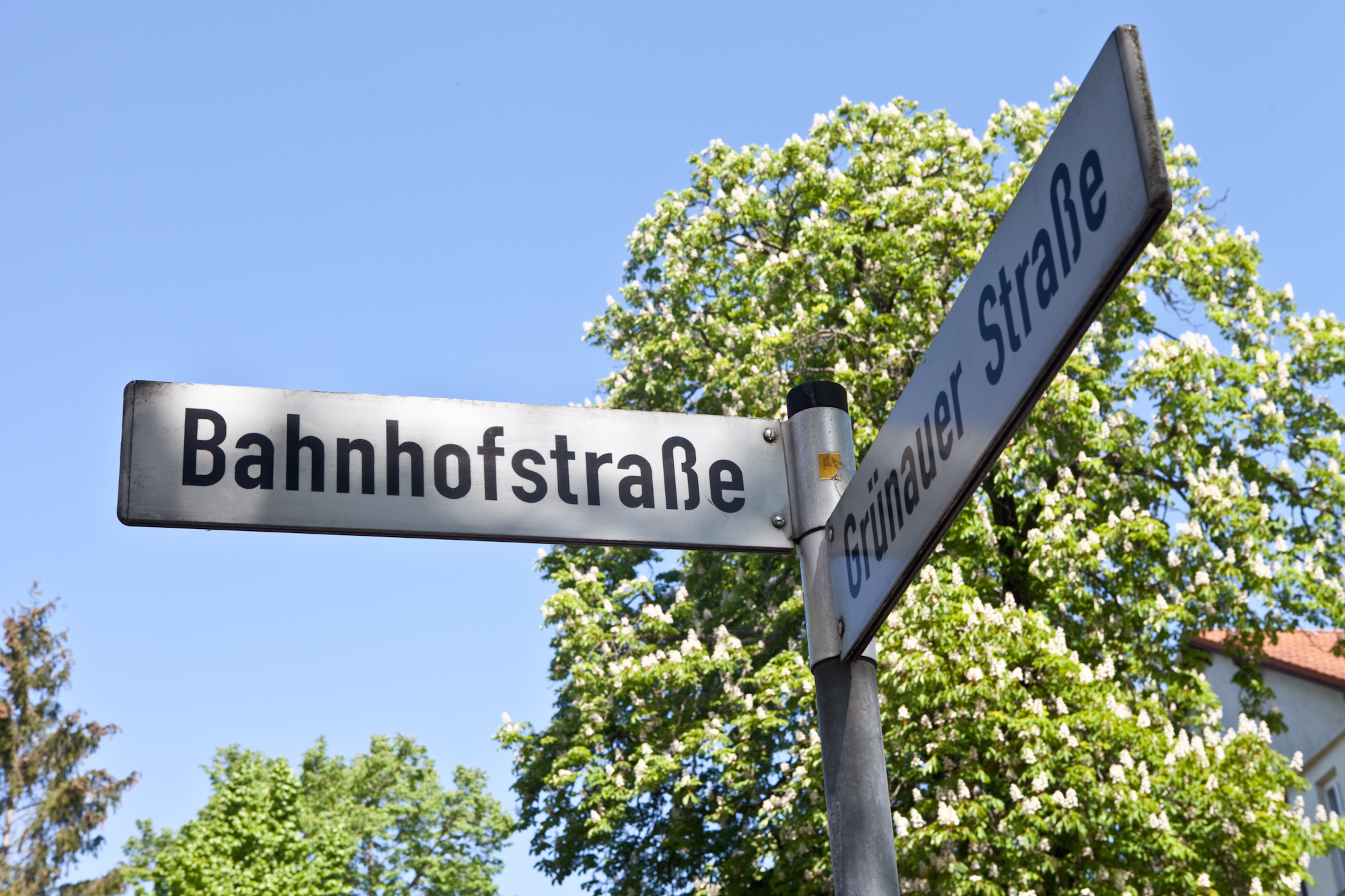 Wegweiser mit Schriftzug ‚Bahnhofstraße‘, Bäume im Hintergrund – Lageplan.