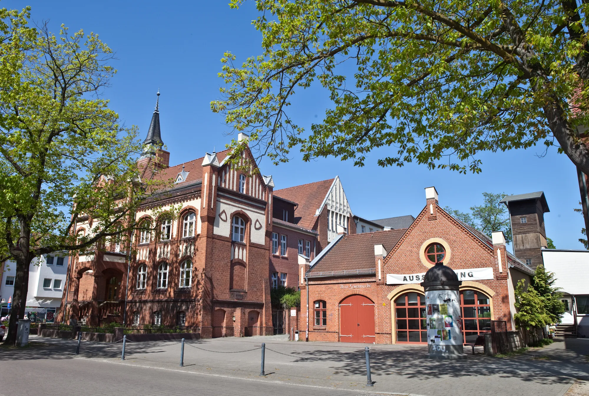 Historisches Gebäude mit roten Backsteinen und Bäumen davor