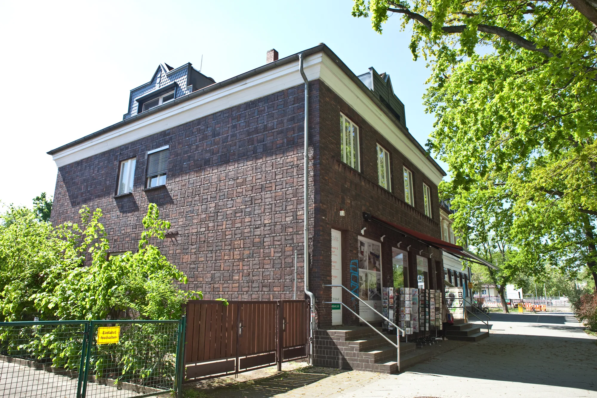 Backsteinbau mit modernen Fenstern und Bäumen.
