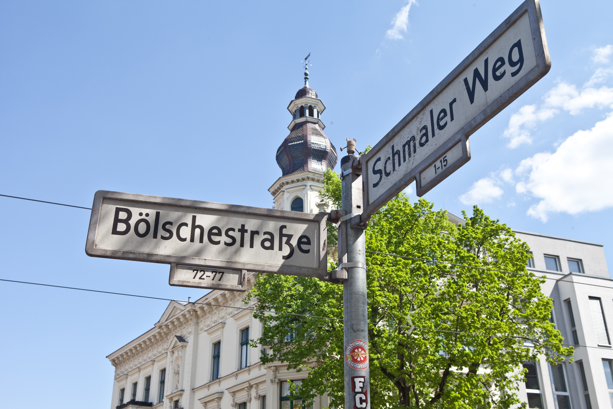 Wegweiser mit Ortsnamen vor Gebäuden – Standortbild.