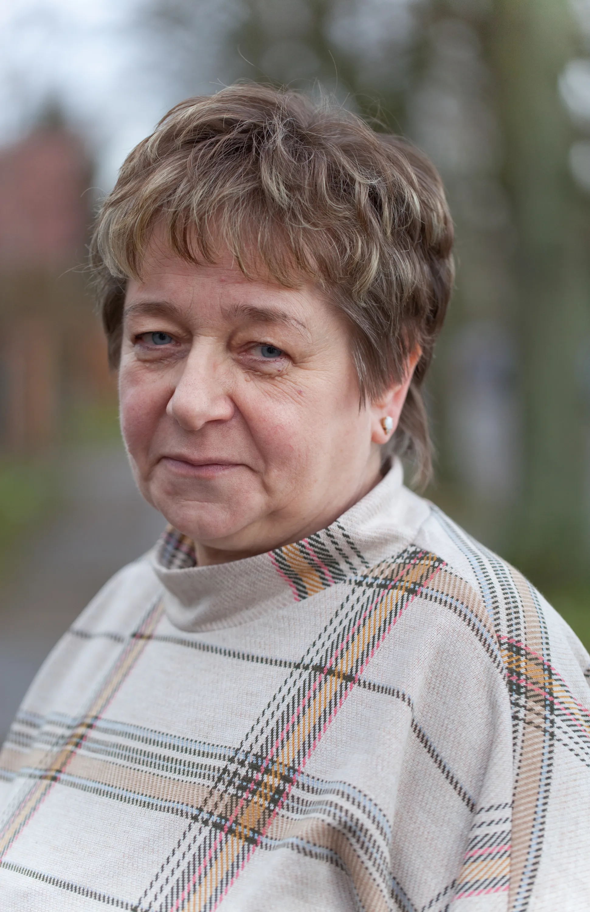 Porträt einer Frau mit Kurzhaarfrisur, karierte Bluse, Naturhintergrund – Mitarbeiterin.