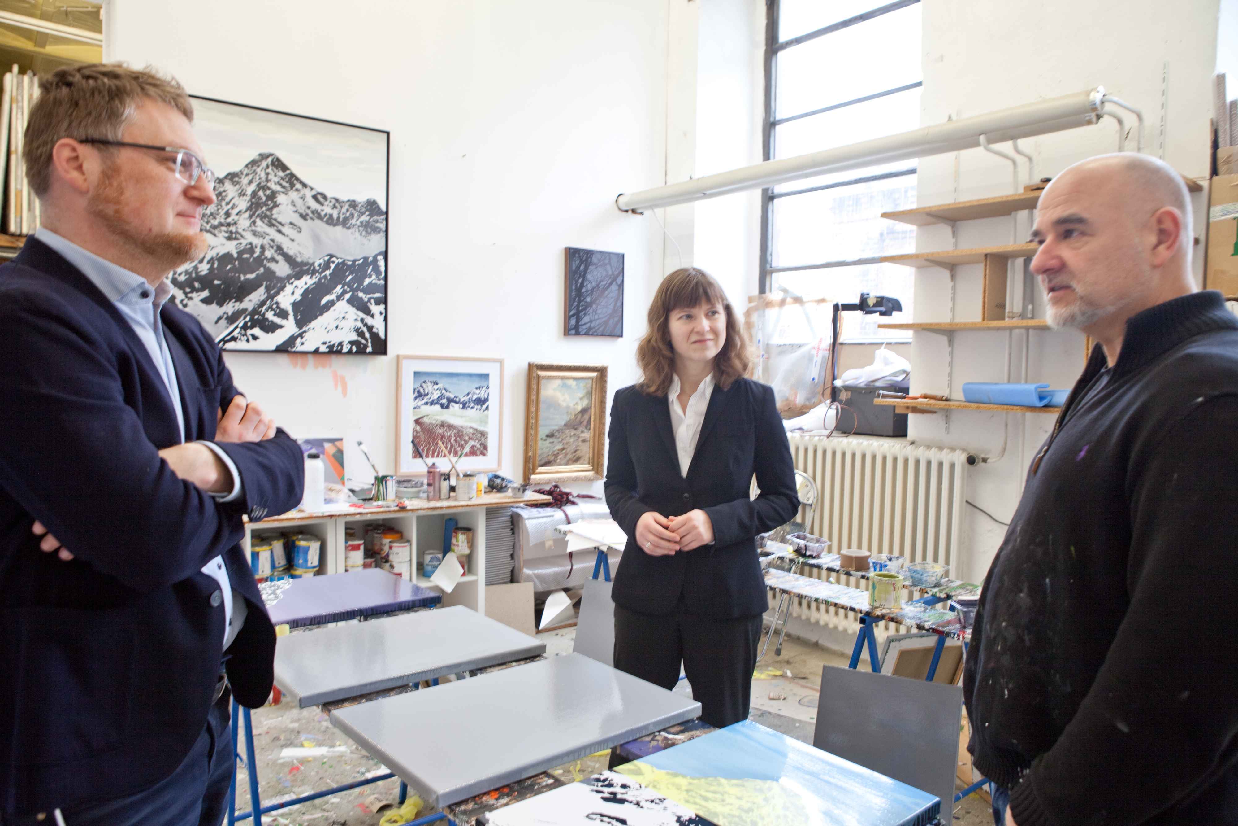 Zwei Männer im Anzug und eine Frau im Büro im Gespräch – Besprechung vor Ort.
